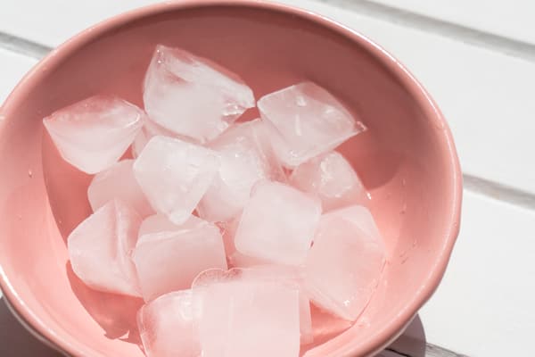 Overhead view of cloudy ice cubes in a pink bowl